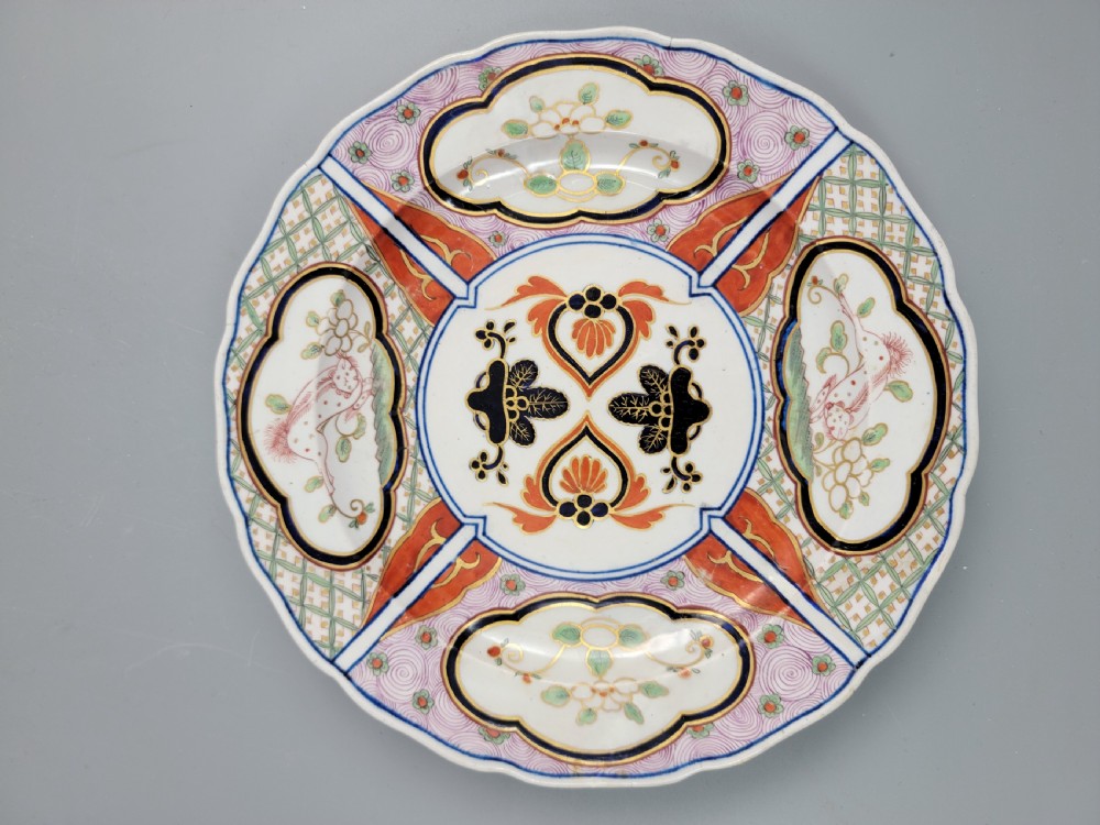 A pair of circular late 18th-century Derby porcelain plates featuring scalloped rims and hand-painted polychrome Kylin pattern designs in orange, cobalt blue, pink, and green. View XVI