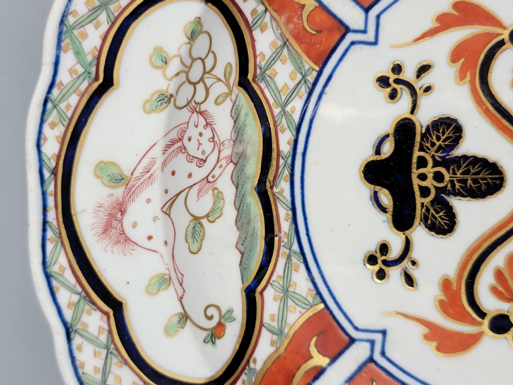 A pair of circular late 18th-century Derby porcelain plates featuring scalloped rims and hand-painted polychrome Kylin pattern designs in orange, cobalt blue, pink, and green. View XVII