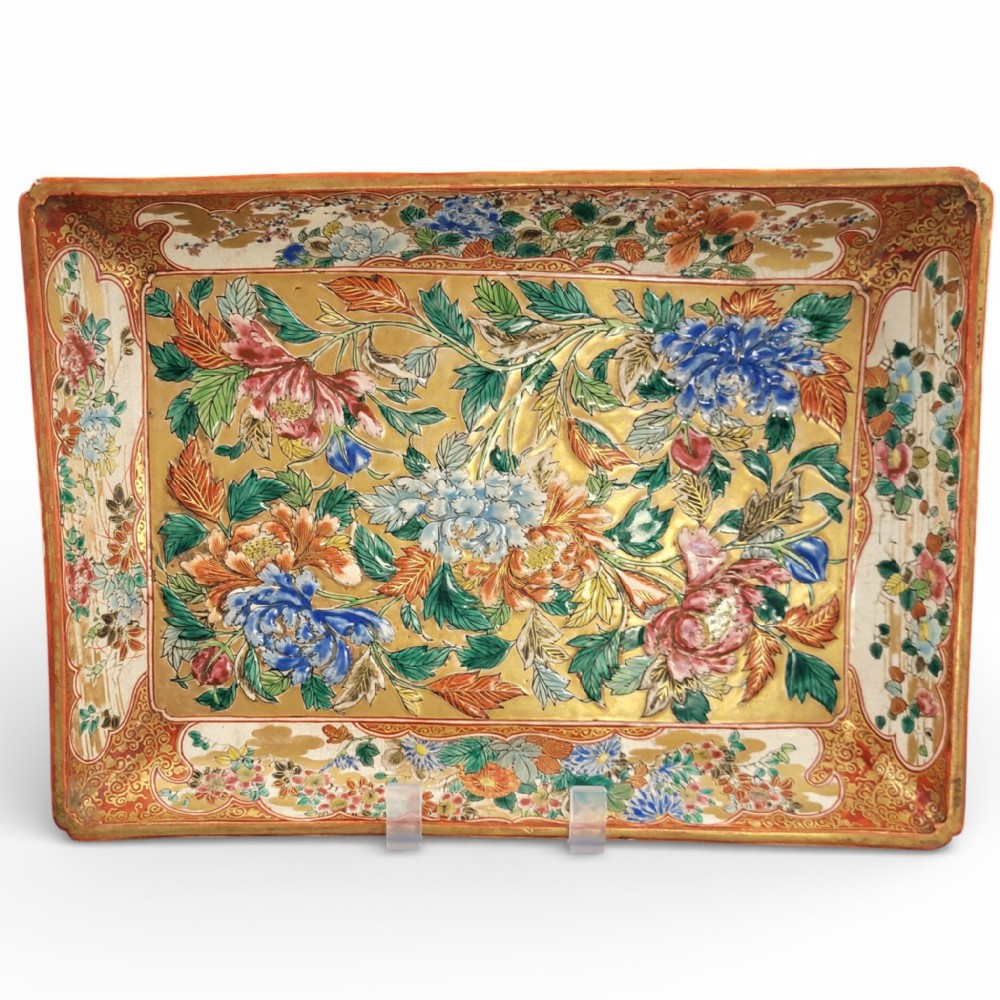 A rectangular Japanese Kutani porcelain platter decorated with polychrome peony blossoms and green leaves over a textured gold background, framed by a floral border.