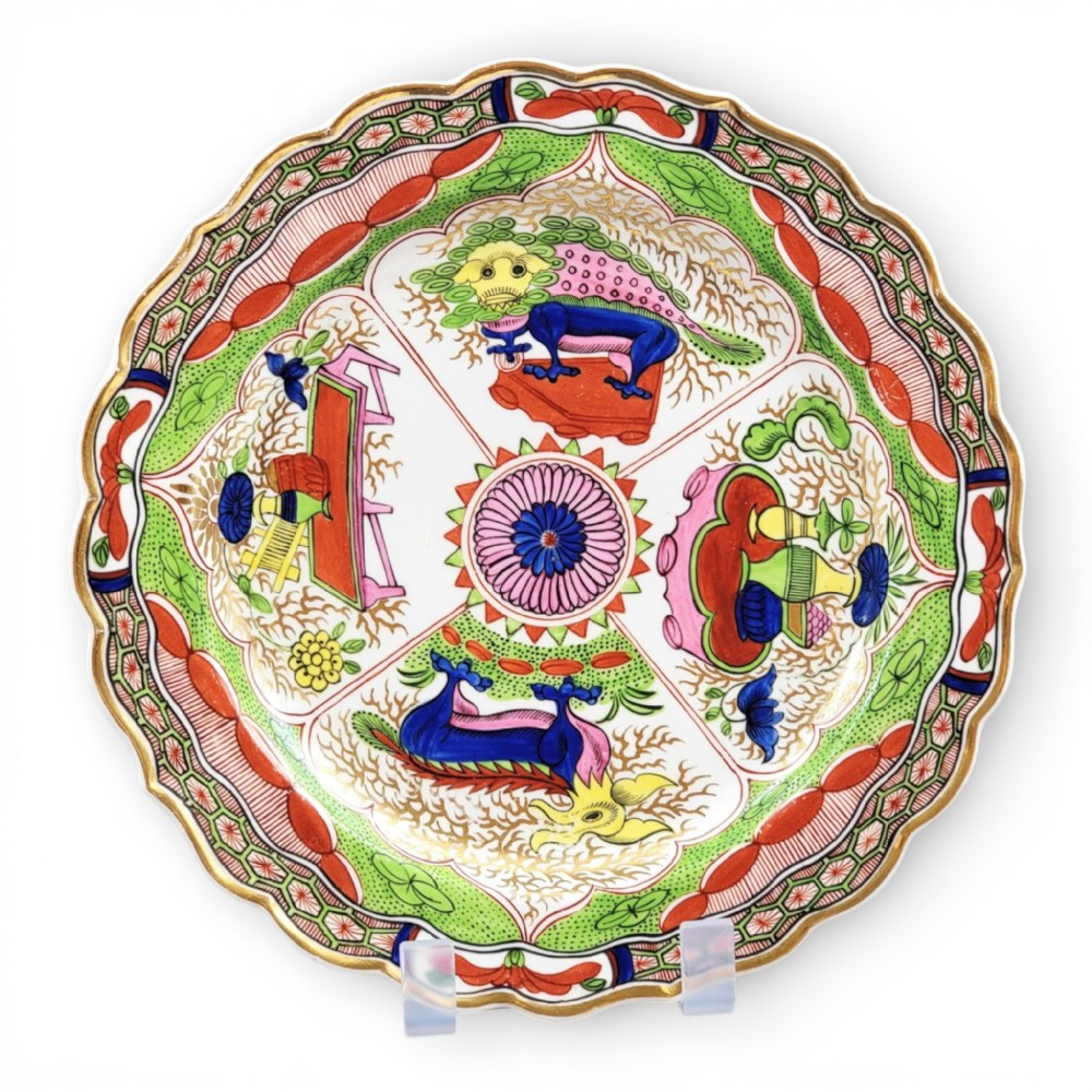 A circular Regency porcelain plate with a scalloped gilded rim and hand-painted dragon in compartments pattern in red, green, and blue enamels.