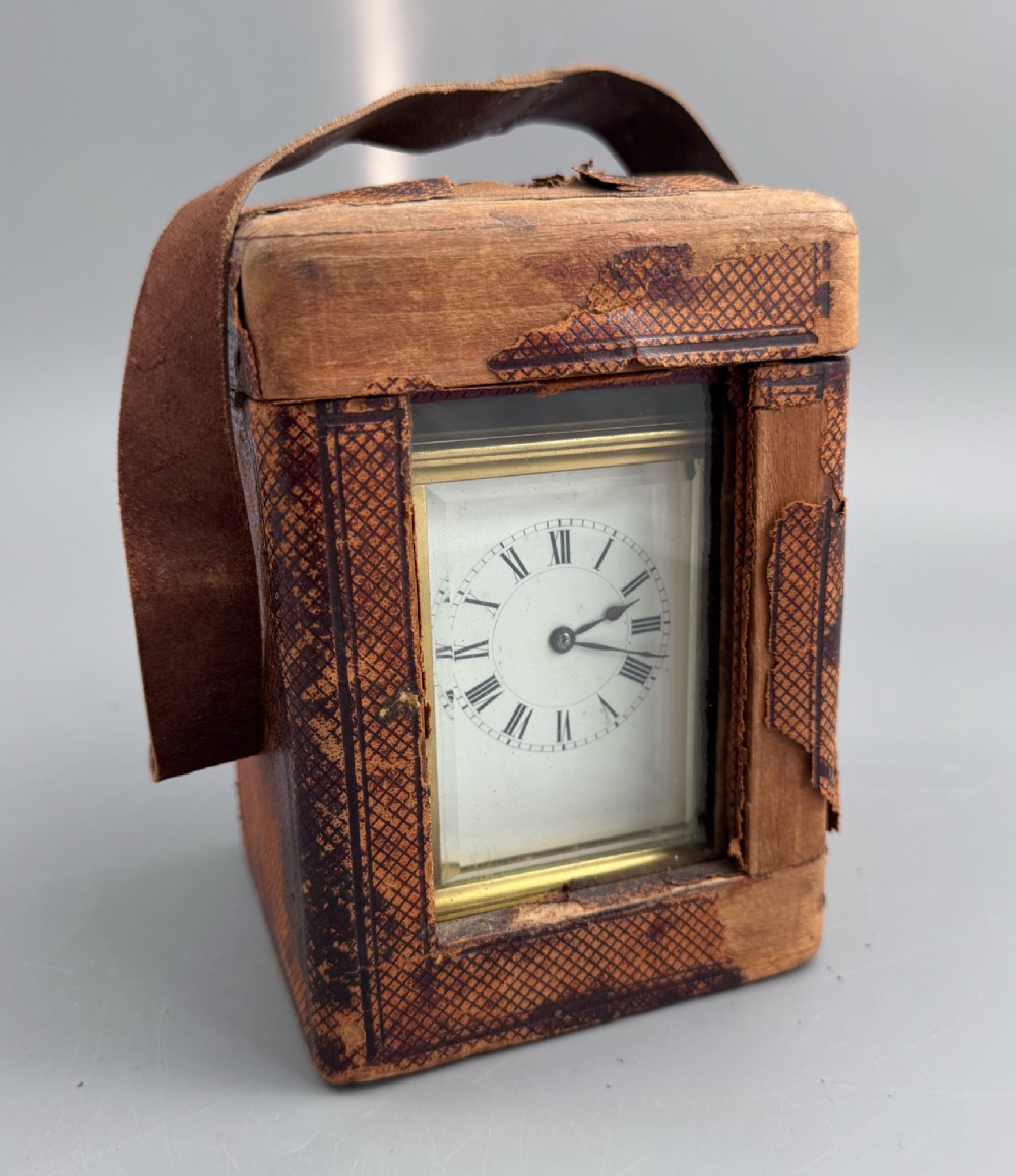 A late 19th-century French brass carriage clock housed inside a protective, textured brown leather travelling case with a leather carrying strap.