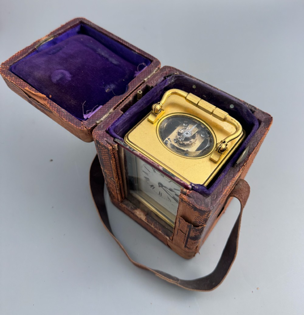A late 19th-century French brass carriage clock housed inside a protective, textured brown leather travelling case with a leather carrying strap. View III