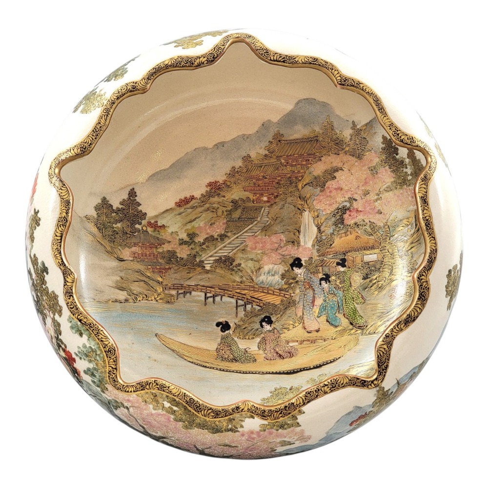 A Japanese Satsuma earthenware bowl with hand-painted figures under trees and gold accents, resting on a dark carved wooden stand. View XII