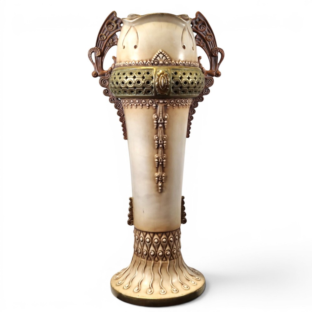 A tall Art Nouveau ceramic vase featuring a cream glaze body, brown reticulated handles, geometric relief beadwork, and a flared pedestal base.