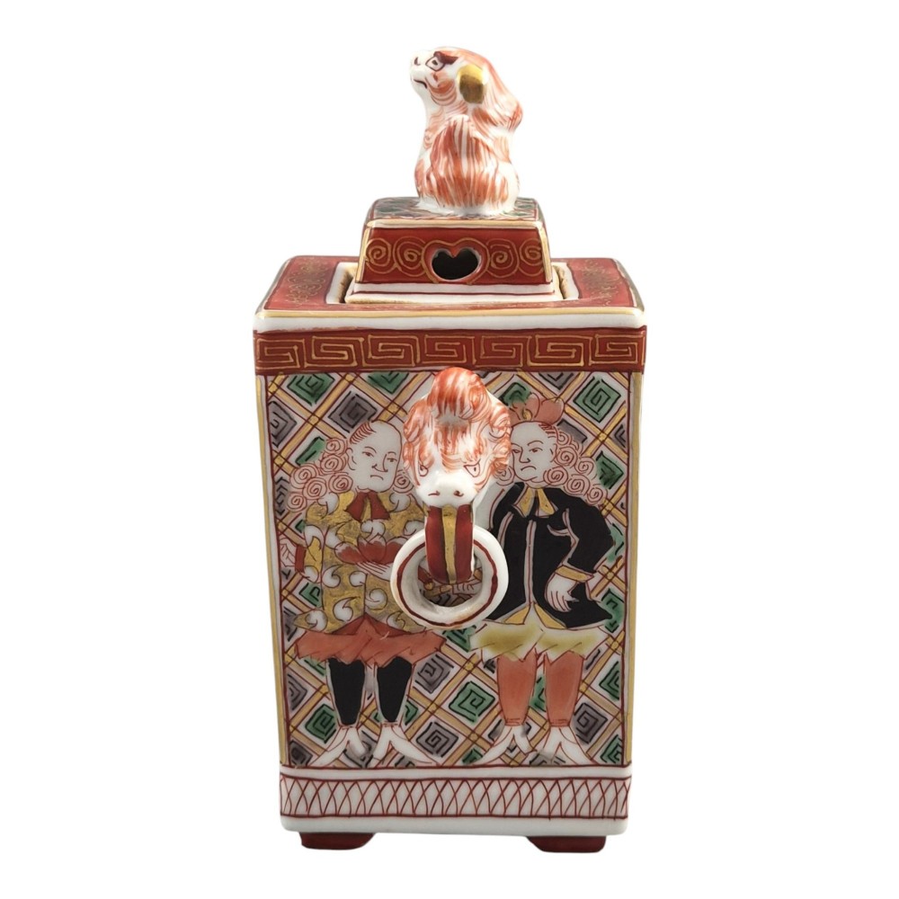 A rectangular Japanese porcelain incense burner featuring hand-painted depictions of a European ship, decorative red enamel borders, animal head handles, and a shishi lion finial on the lid. View II
