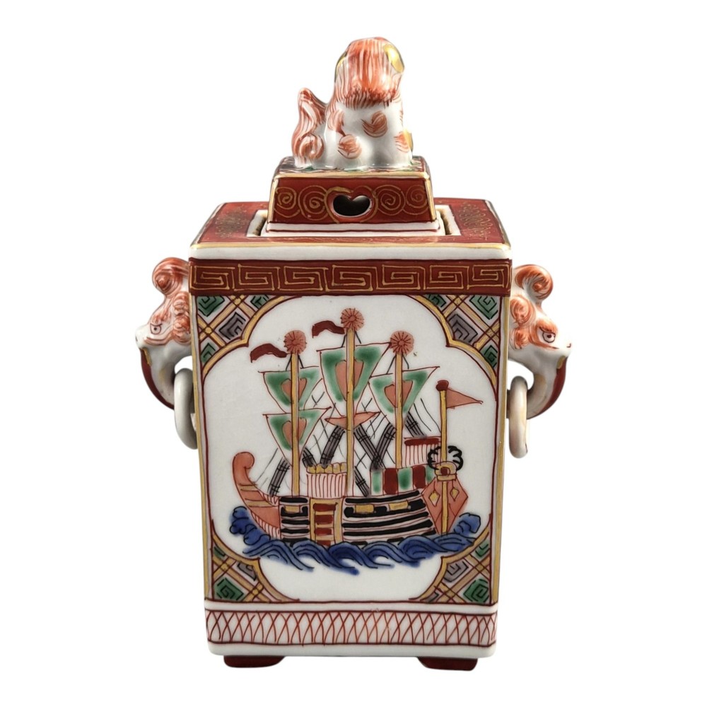 A rectangular Japanese porcelain incense burner featuring hand-painted depictions of a European ship, decorative red enamel borders, animal head handles, and a shishi lion finial on the lid. View III