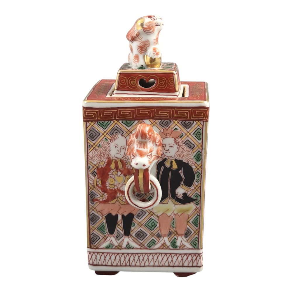 A rectangular Japanese porcelain incense burner featuring hand-painted depictions of a European ship, decorative red enamel borders, animal head handles, and a shishi lion finial on the lid. View IV