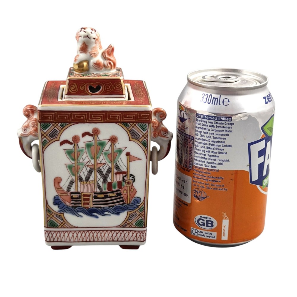 A rectangular Japanese porcelain incense burner featuring hand-painted depictions of a European ship, decorative red enamel borders, animal head handles, and a shishi lion finial on the lid. View XV