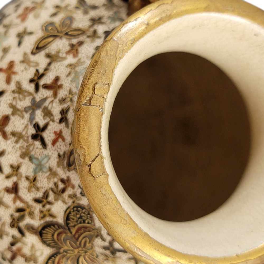 A pair of baluster-shaped Japanese Satsuma earthenware vases decorated with a dense pattern of polychrome butterflies and gold lion-dog side handles. View II