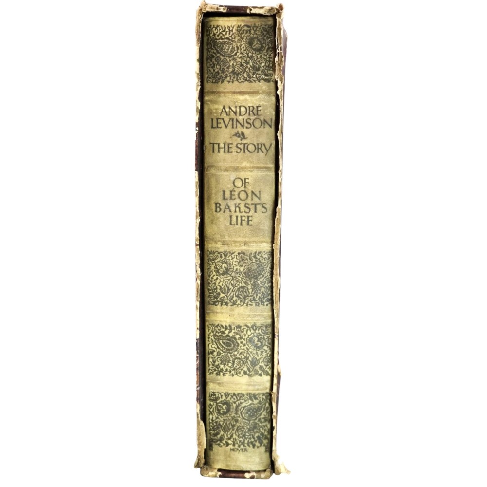 The spine of an antique hardcover book featuring intricate gilt floral patterns and lettered text reading The Story of Leon Baksts Life by Andre Levinson.