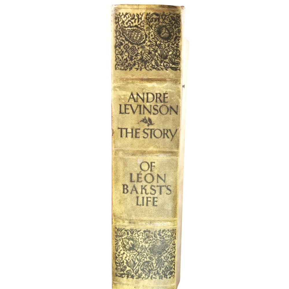 The spine of an antique hardcover book featuring intricate gilt floral patterns and lettered text reading The Story of Leon Baksts Life by Andre Levinson. View V
