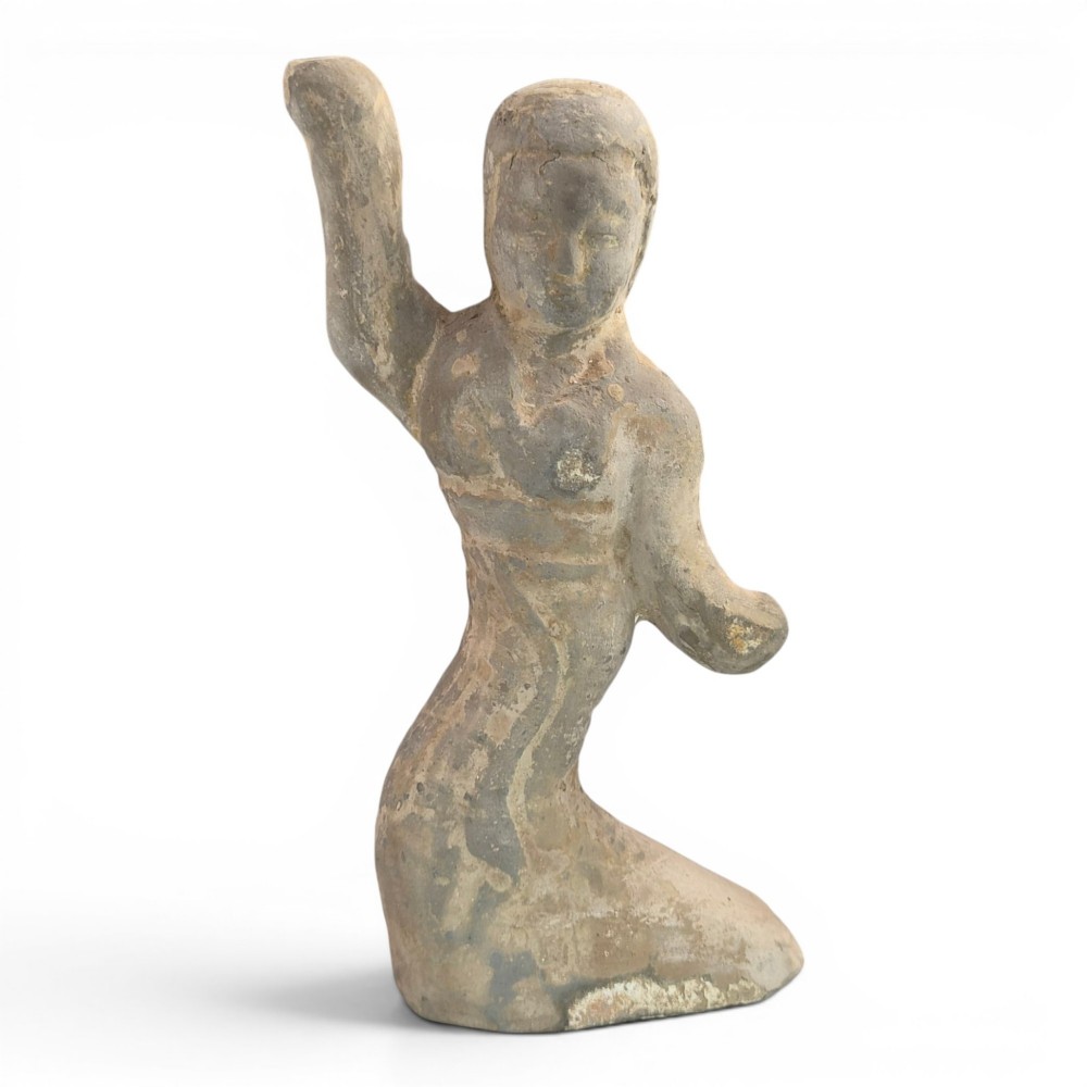 An ancient grey earthenware figure of a dancer in an S-shaped posture with one arm raised and an unglazed finish.