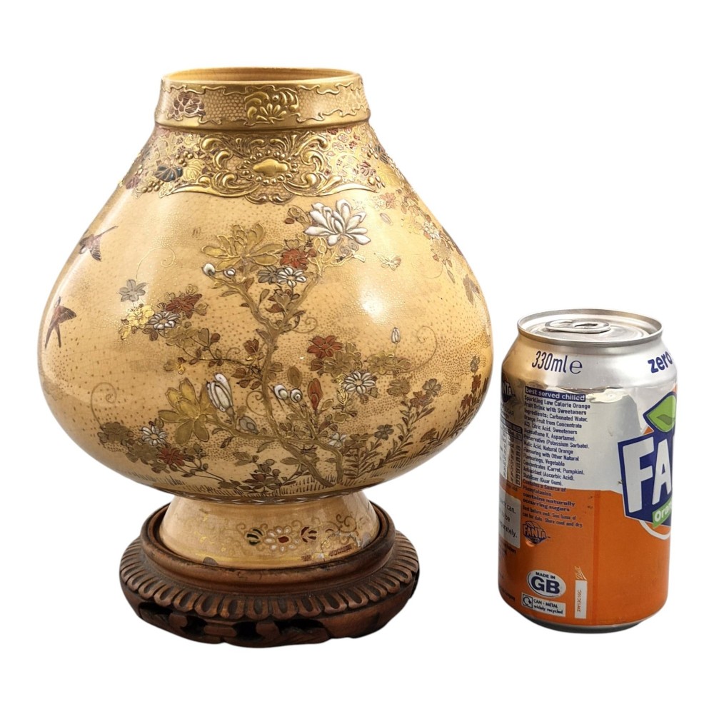 A bulbous Japanese Satsuma earthenware vase featuring a cream crackle glaze, intricate floral gilding, birds, and a carved dark wooden display stand. View VII
