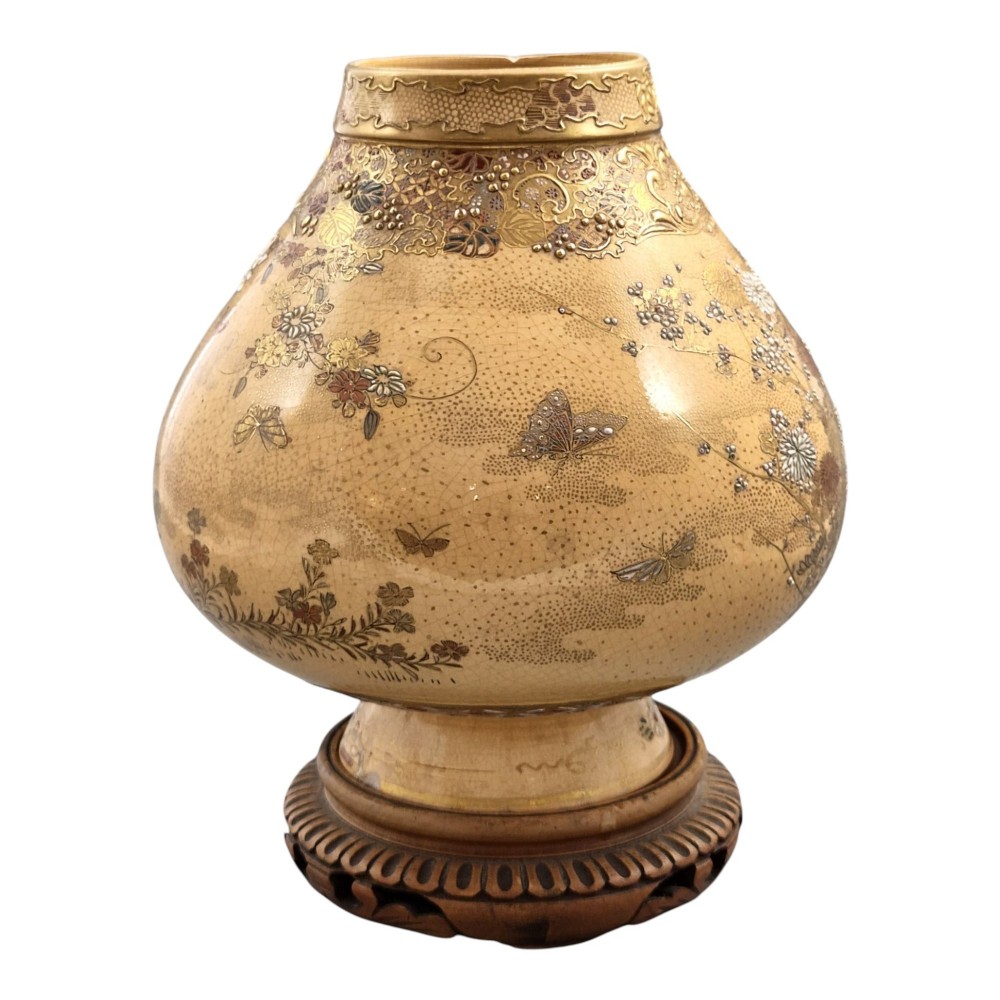 A bulbous Japanese Satsuma earthenware vase featuring a cream crackle glaze, intricate floral gilding, birds, and a carved dark wooden display stand. View VIII