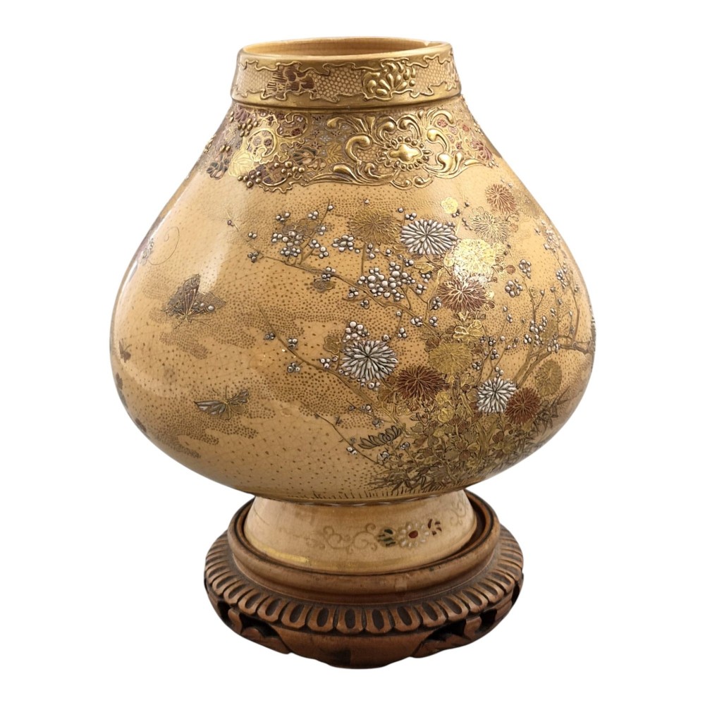 A bulbous Japanese Satsuma earthenware vase featuring a cream crackle glaze, intricate floral gilding, birds, and a carved dark wooden display stand. View IX