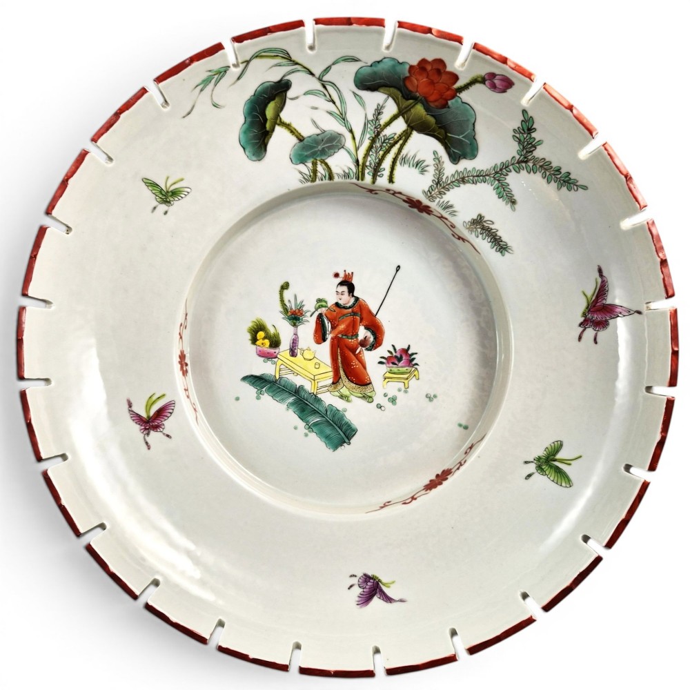 A late Qing dynasty Chinese Famille Rose porcelain dish featuring a hand-painted central figure, lotus blossoms, butterflies, and a distinct red castellated rim.
