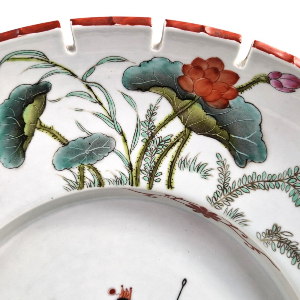 A late Qing dynasty Chinese Famille Rose porcelain dish featuring a hand-painted central figure, lotus blossoms, butterflies, and a distinct red castellated rim. View V