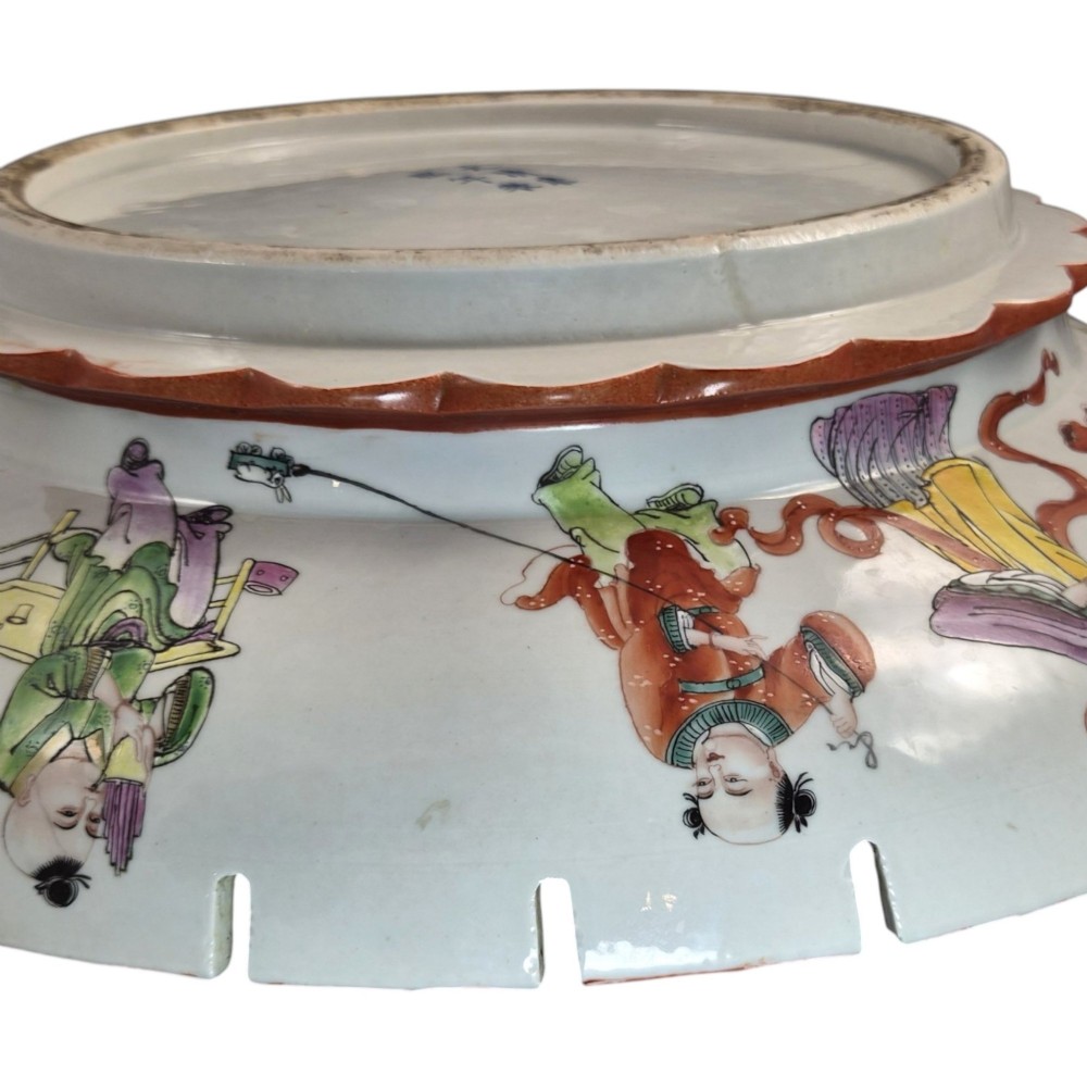A late Qing dynasty Chinese Famille Rose porcelain dish featuring a hand-painted central figure, lotus blossoms, butterflies, and a distinct red castellated rim. View XIV