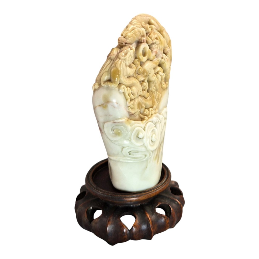A carved cream and tan Shoushan stone sculpture depicting a dragon amongst clouds set upon a dark turned wooden base. View II