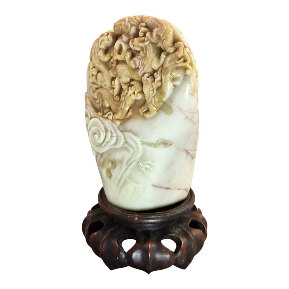 A carved cream and tan Shoushan stone sculpture depicting a dragon amongst clouds set upon a dark turned wooden base. View V
