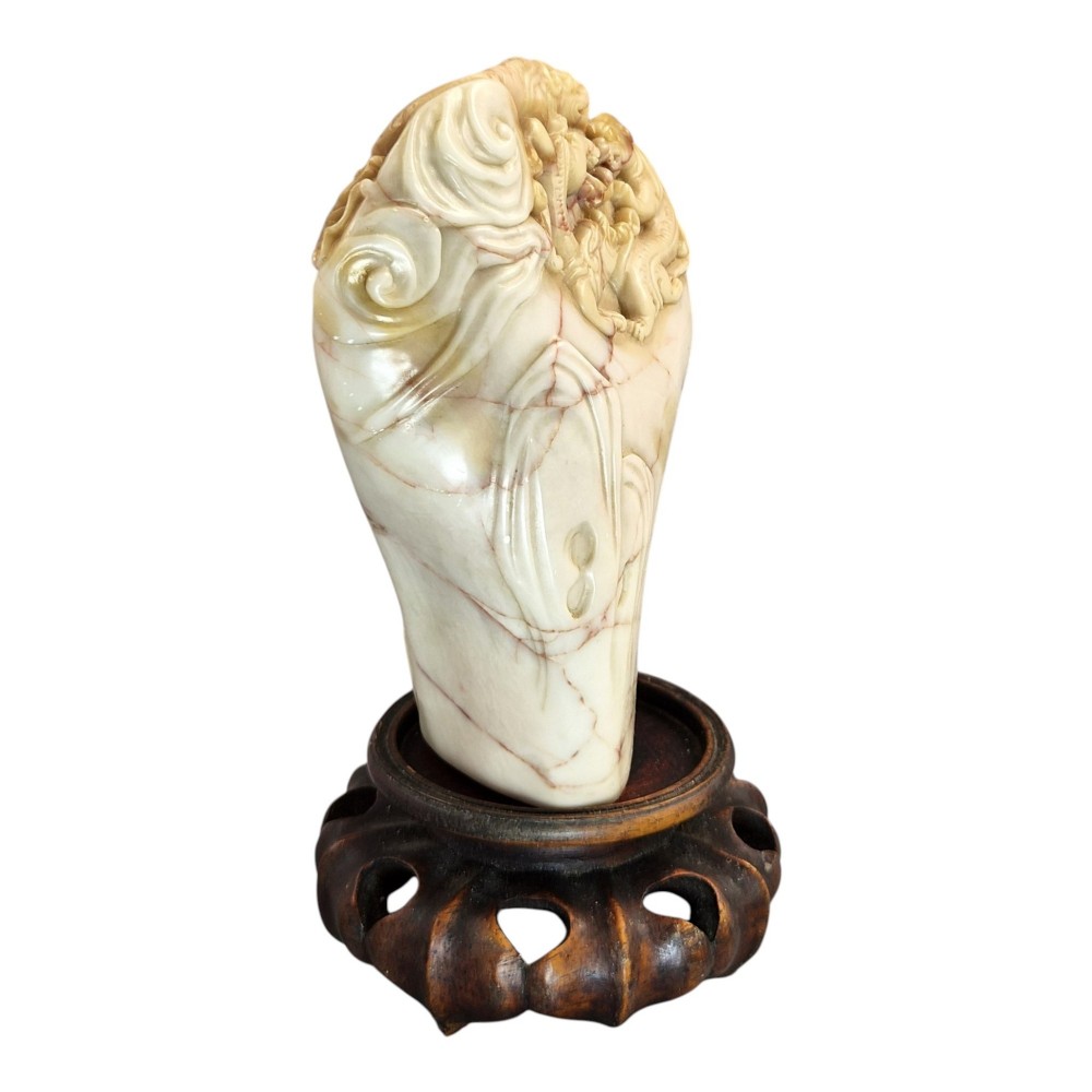 A carved cream and tan Shoushan stone sculpture depicting a dragon amongst clouds set upon a dark turned wooden base. View VI