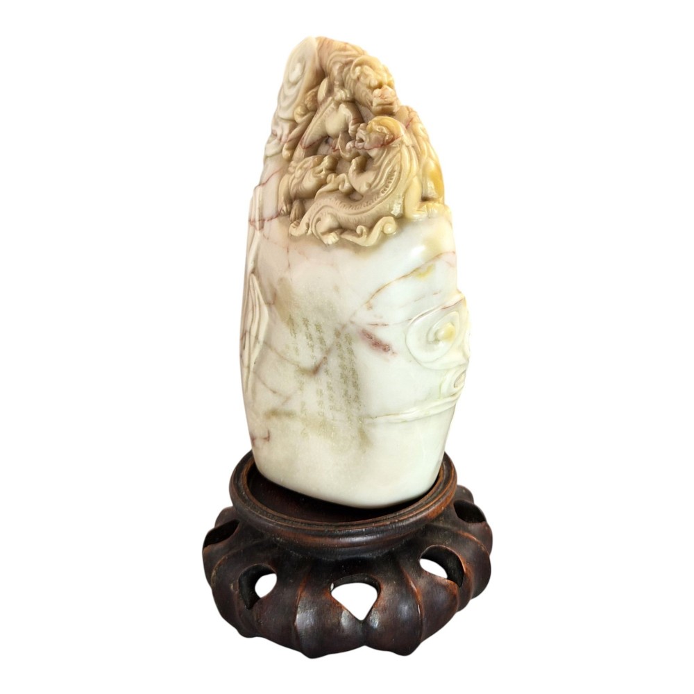 A carved cream and tan Shoushan stone sculpture depicting a dragon amongst clouds set upon a dark turned wooden base. View IX