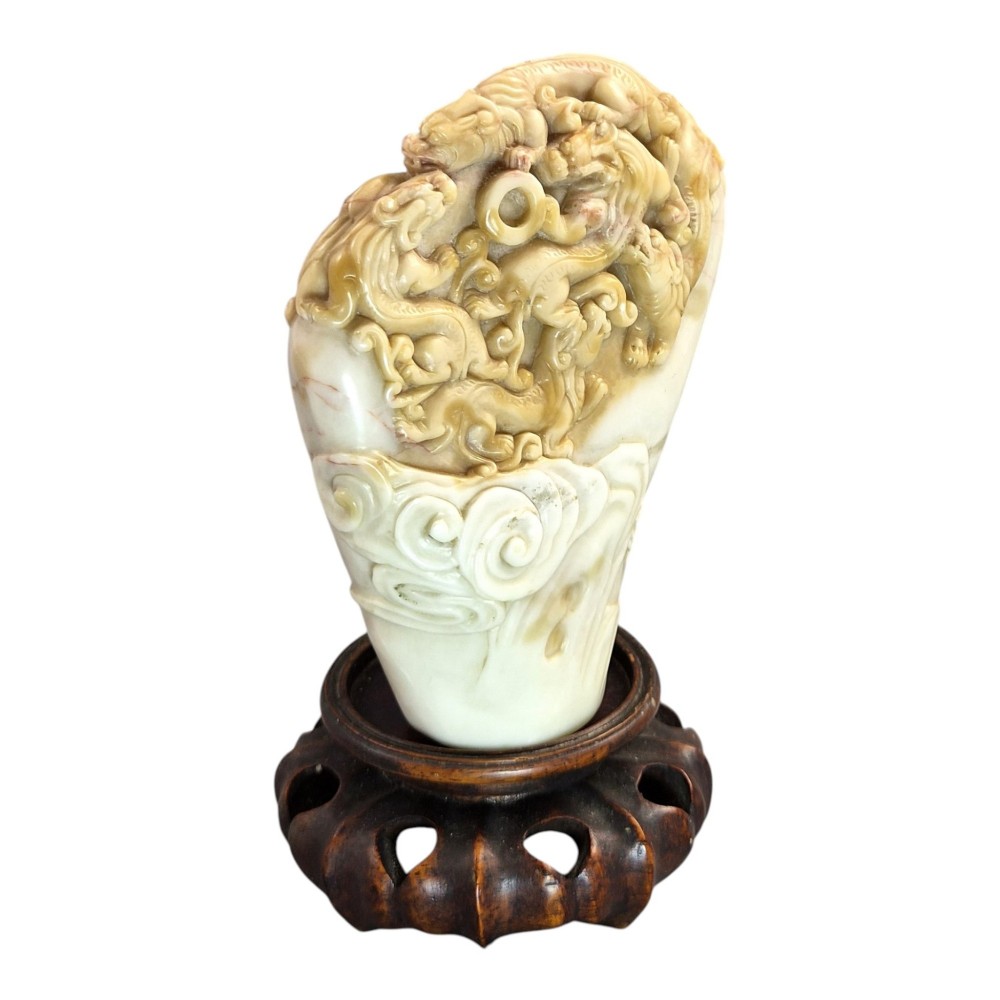 A carved cream and tan Shoushan stone sculpture depicting a dragon amongst clouds set upon a dark turned wooden base. View X