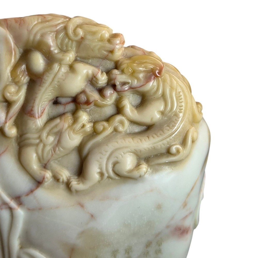 A carved cream and tan Shoushan stone sculpture depicting a dragon amongst clouds set upon a dark turned wooden base. View XI
