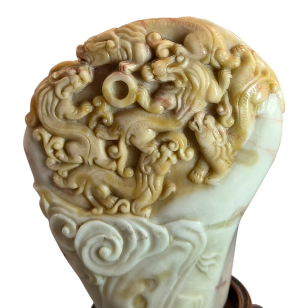 A carved cream and tan Shoushan stone sculpture depicting a dragon amongst clouds set upon a dark turned wooden base. View XIII