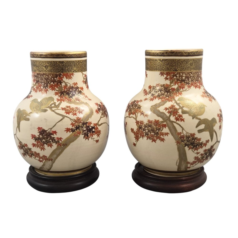 A pair of bulbous cream-coloured Japanese Satsuma earthenware vases decorated with gilt birds and autumnal foliage on dark carved wood stands. View IV