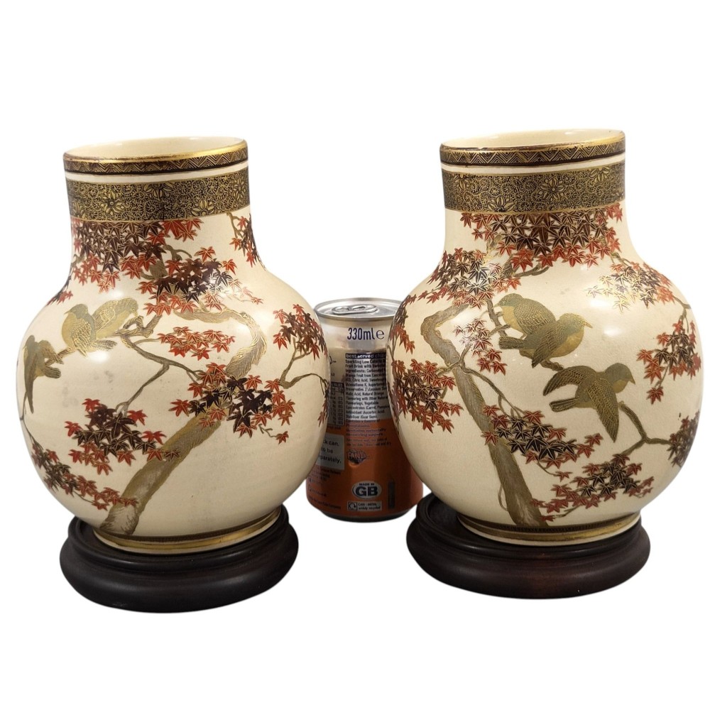 A pair of bulbous cream-coloured Japanese Satsuma earthenware vases decorated with gilt birds and autumnal foliage on dark carved wood stands. View XI