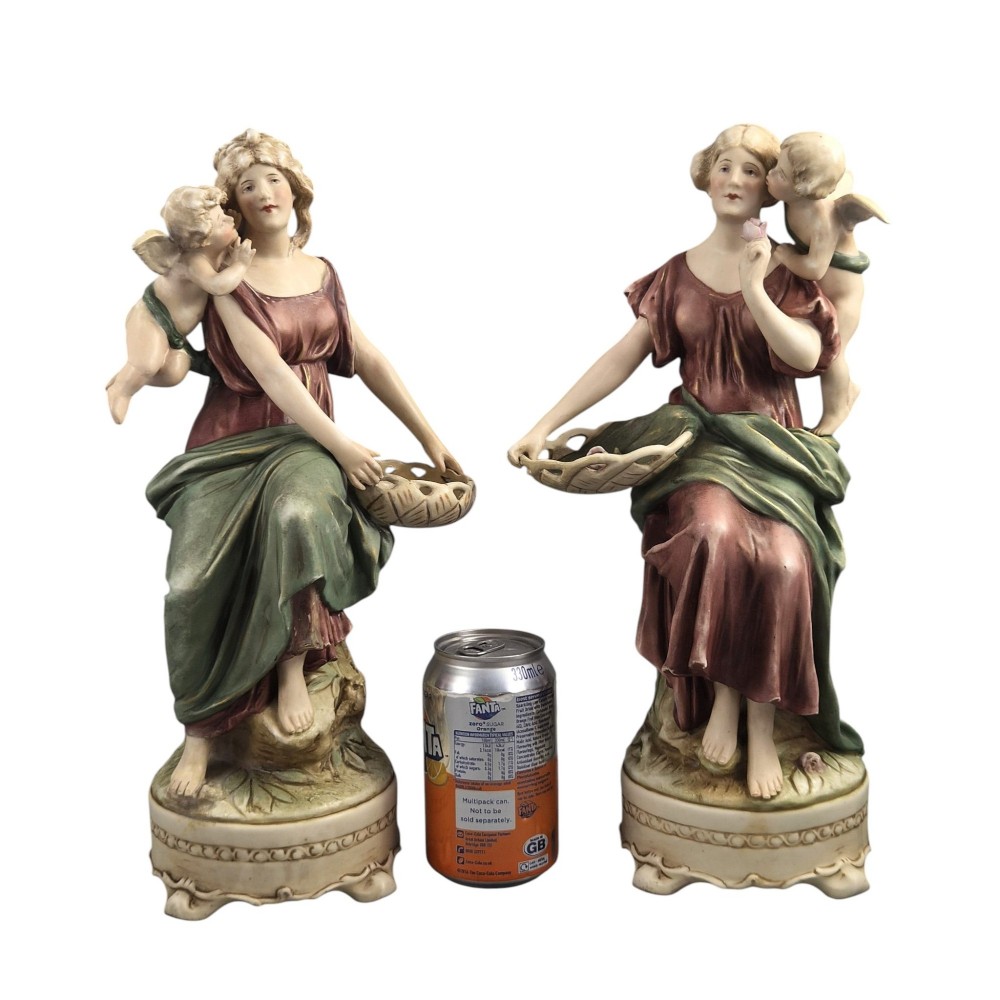 A pair of Royal Dux Art Nouveau porcelain figurines depicting classical maidens with winged cherubs and openwork baskets. View IX
