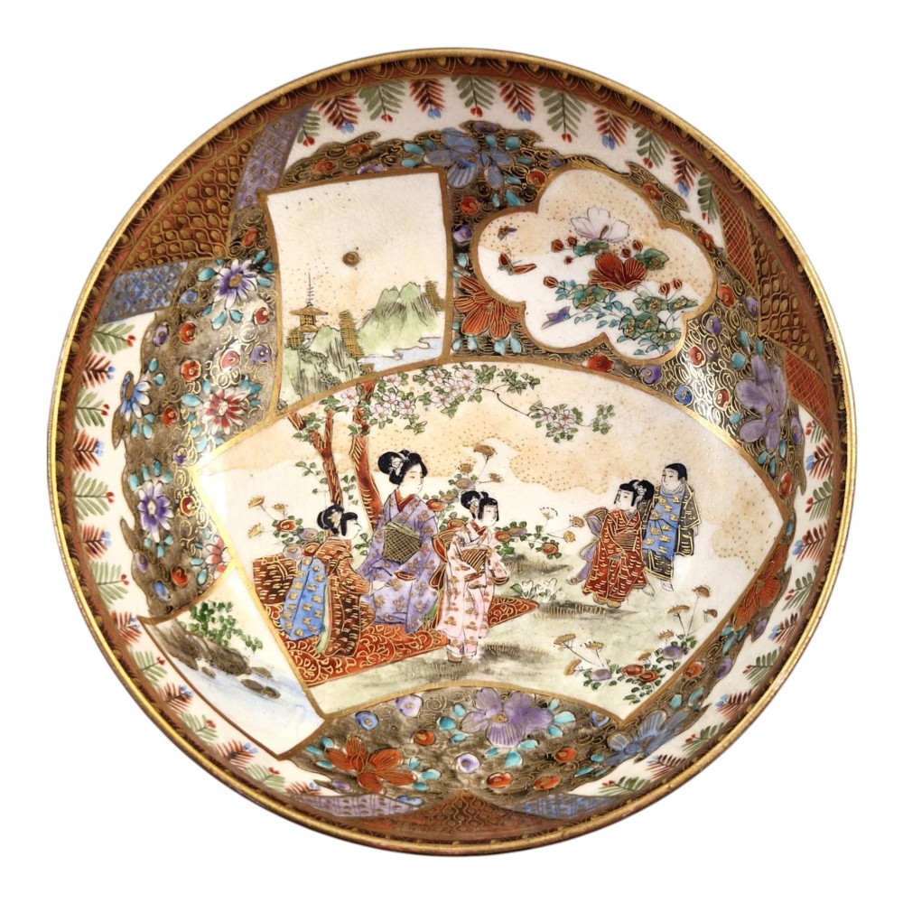 An antique Meiji period Japanese Satsuma earthenware bowl featuring hand-painted floral panels and gold detailing, elevated on a carved dark wooden base. View II