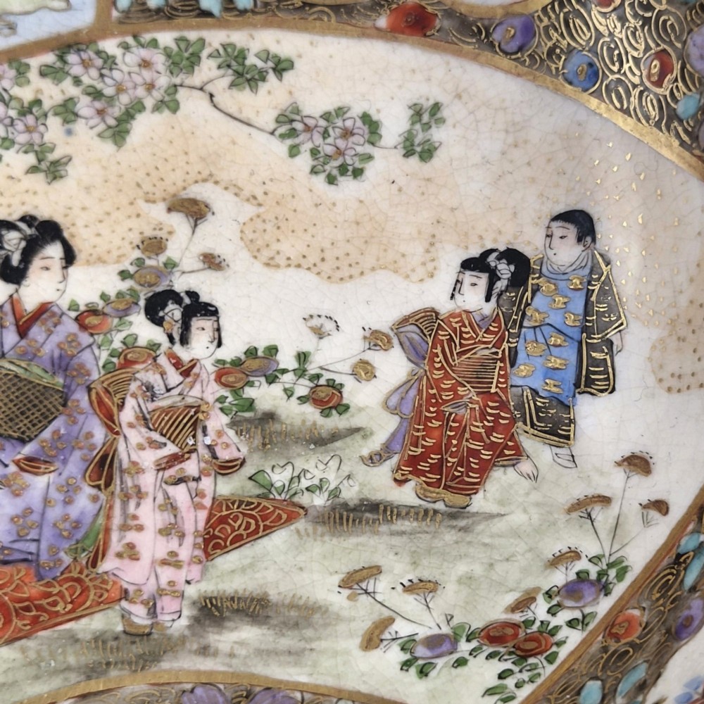 An antique Meiji period Japanese Satsuma earthenware bowl featuring hand-painted floral panels and gold detailing, elevated on a carved dark wooden base. View XI