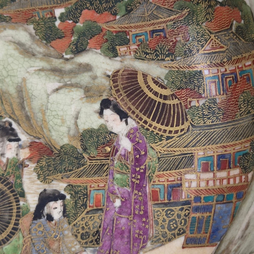 An antique cream earthenware bowl resting on a carved wooden base, decorated inside with hand-painted Japanese landscapes and figures, and finished with a bamboo pattern around the exterior. View II