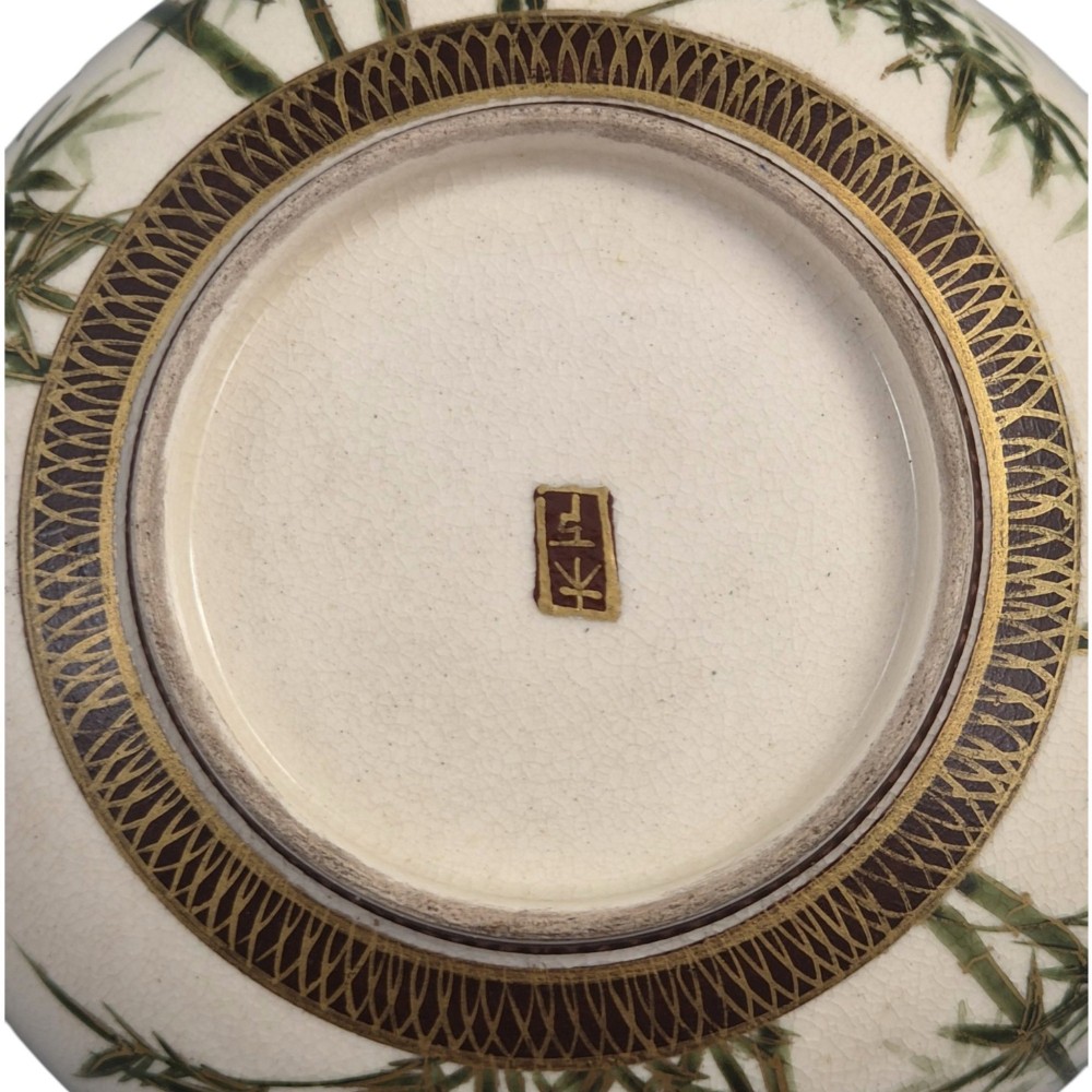 An antique cream earthenware bowl resting on a carved wooden base, decorated inside with hand-painted Japanese landscapes and figures, and finished with a bamboo pattern around the exterior. View III