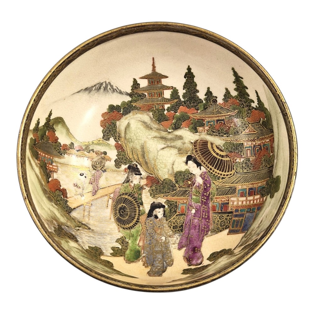 An antique cream earthenware bowl resting on a carved wooden base, decorated inside with hand-painted Japanese landscapes and figures, and finished with a bamboo pattern around the exterior. View V
