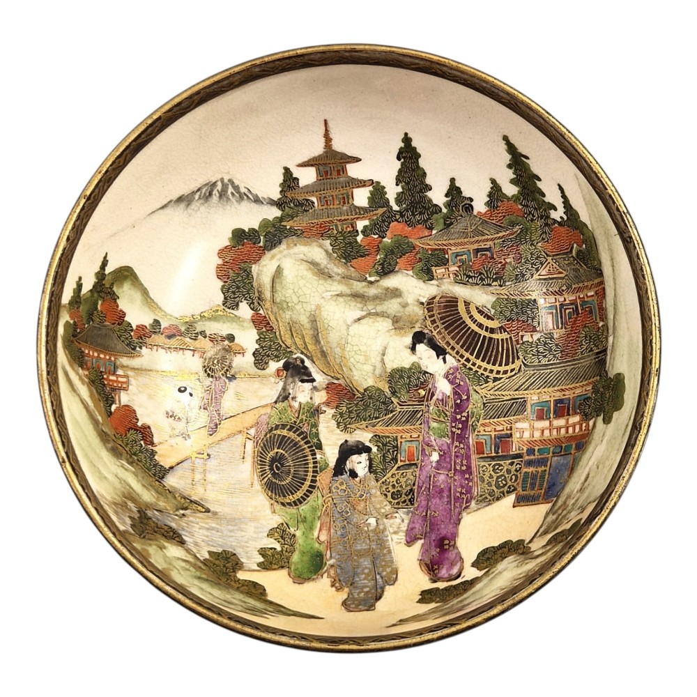 An antique cream earthenware bowl resting on a carved wooden base, decorated inside with hand-painted Japanese landscapes and figures, and finished with a bamboo pattern around the exterior. View XI