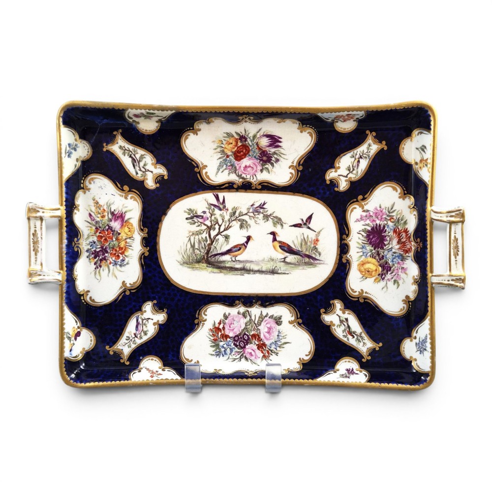 A rectangular mid-19th-century English porcelain tray featuring a dark cobalt blue ground, hand-painted exotic birds in a central oval vignette, floral reserves, and gilt handles.