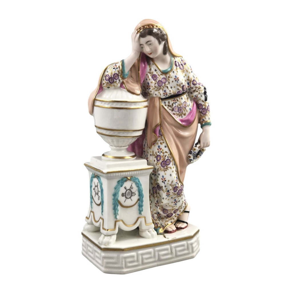 A Neoclassical porcelain figure depicting a draped female leaning against a gilded urn on a pedestal. View II