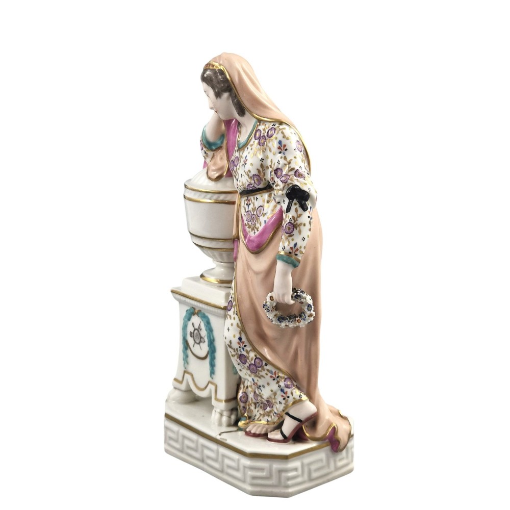 A Neoclassical porcelain figure depicting a draped female leaning against a gilded urn on a pedestal. View III