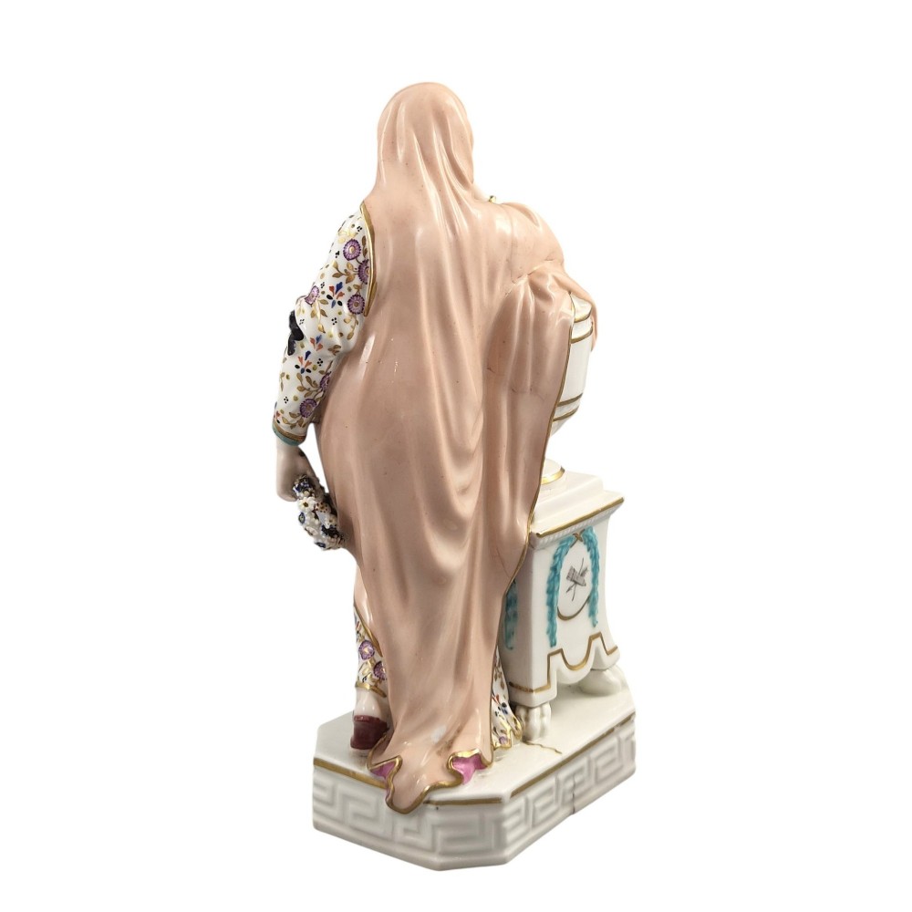 A Neoclassical porcelain figure depicting a draped female leaning against a gilded urn on a pedestal. View IV