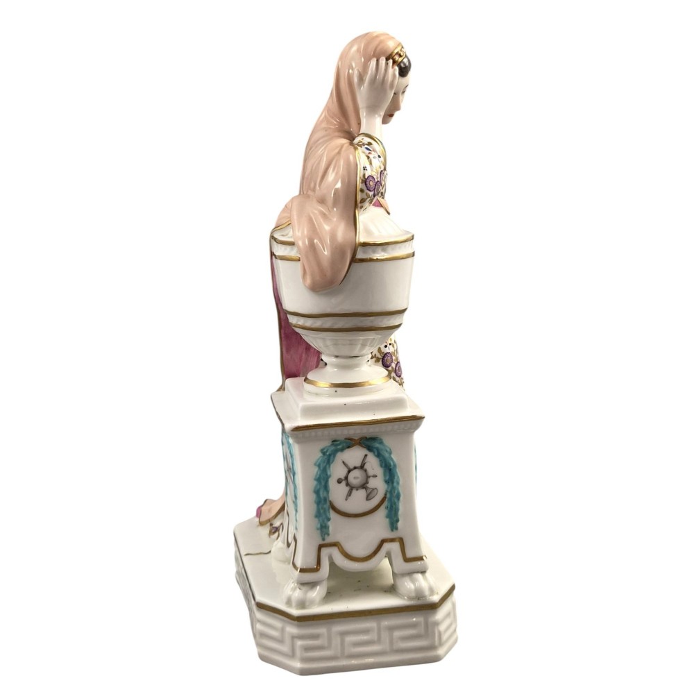 A Neoclassical porcelain figure depicting a draped female leaning against a gilded urn on a pedestal. View VI