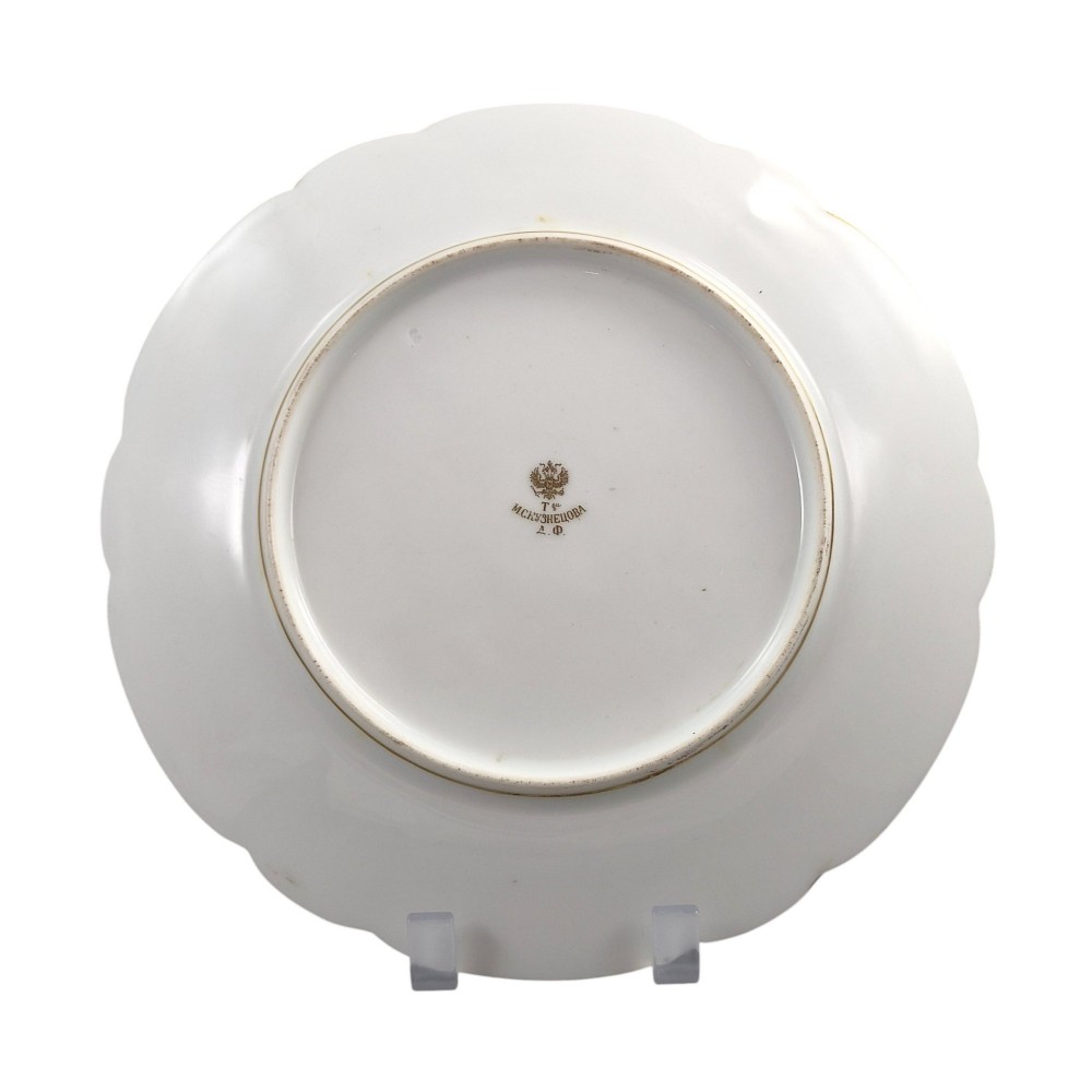 A white round porcelain plate featuring a thick cobalt blue scalloped border and a gilded Imperial monogram topped with a crown. View V