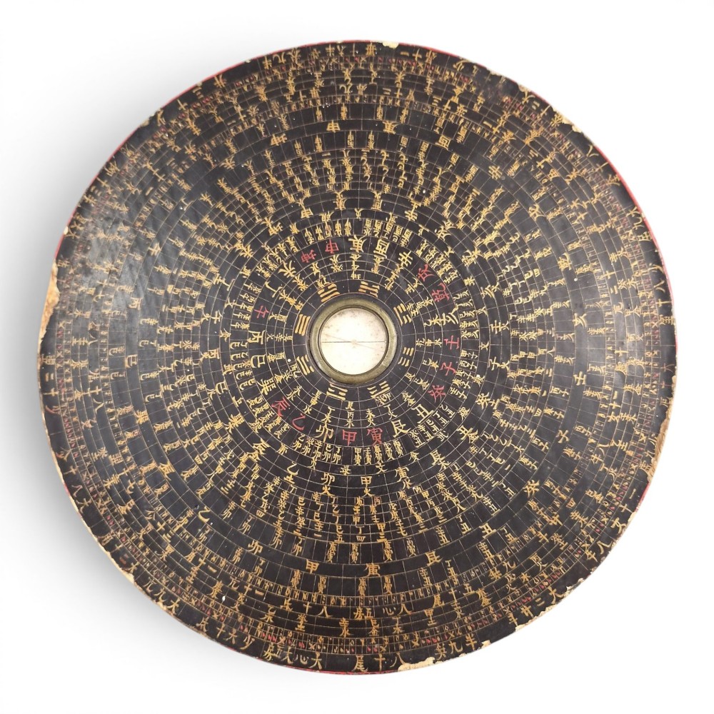 A circular antique Chinese Luopan geomantic compass crafted from dark lacquered wood featuring multiple concentric rings of gilded Chinese characters and a central brass magnetic dial.