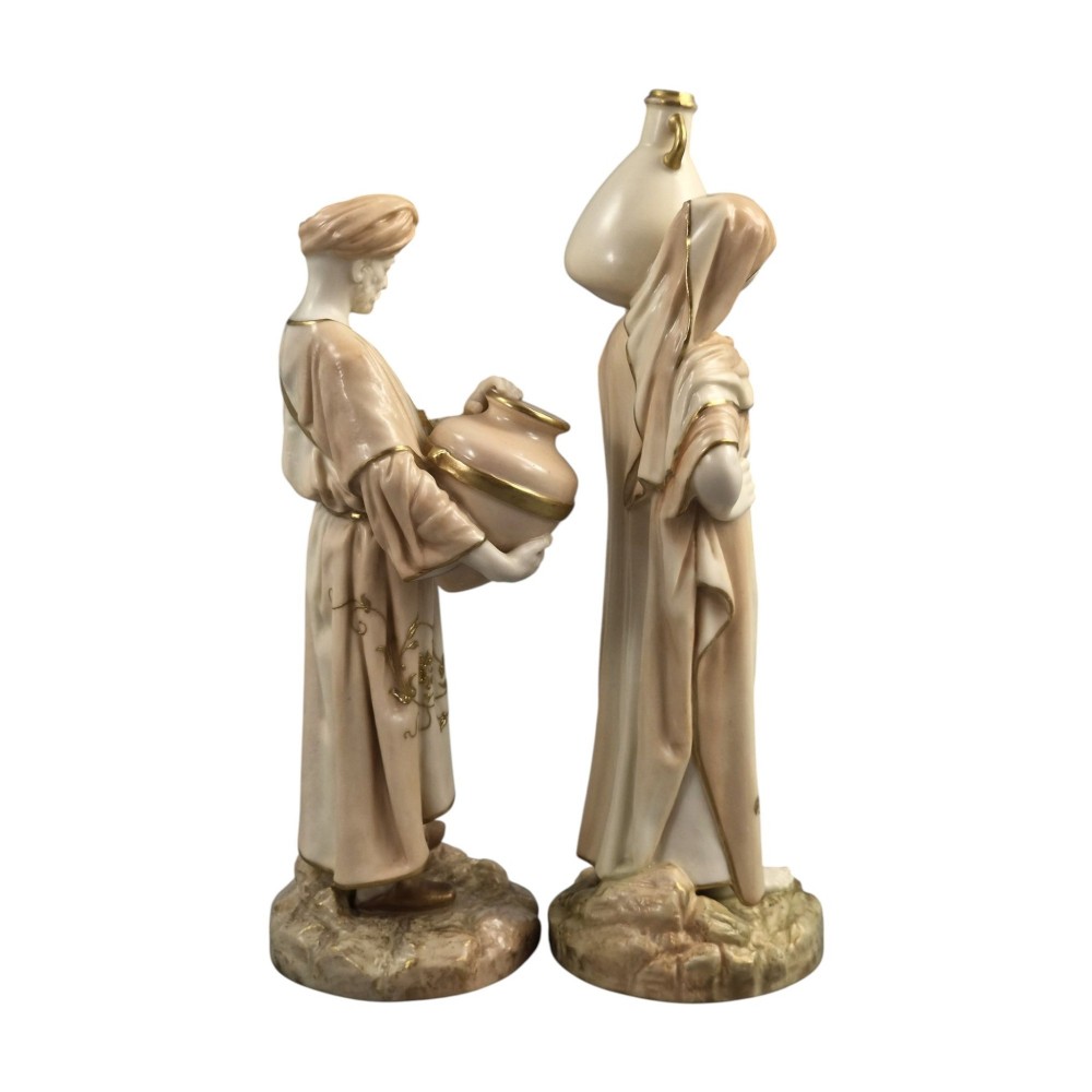 A pair of Royal Worcester blush ivory porcelain figures depicting a male and female Cairo water carrier with gilded accents. View IV