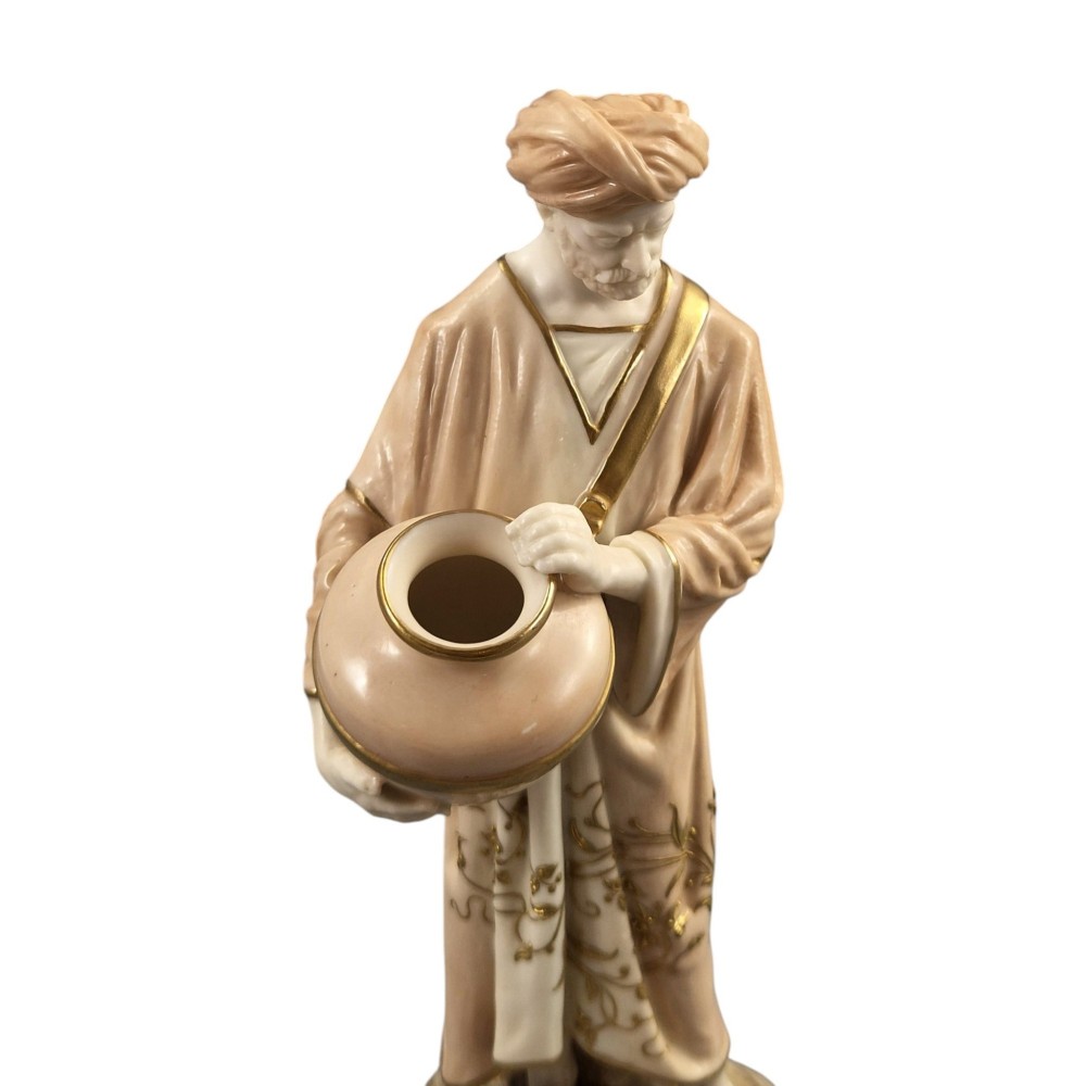 A pair of Royal Worcester blush ivory porcelain figures depicting a male and female Cairo water carrier with gilded accents. View VI