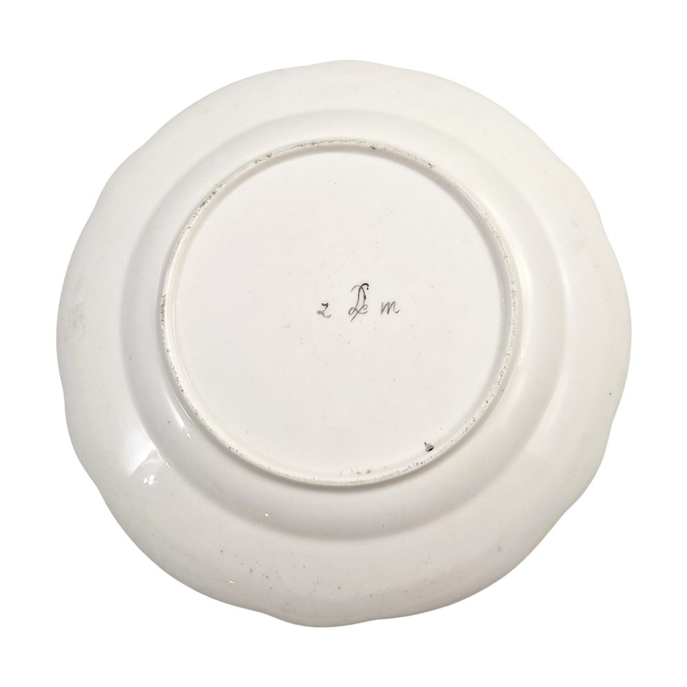 An 18th-century circular white soft-paste porcelain plate decorated with hand-painted floral sprays and a scalloped rim with blue feathered scroll details. View V