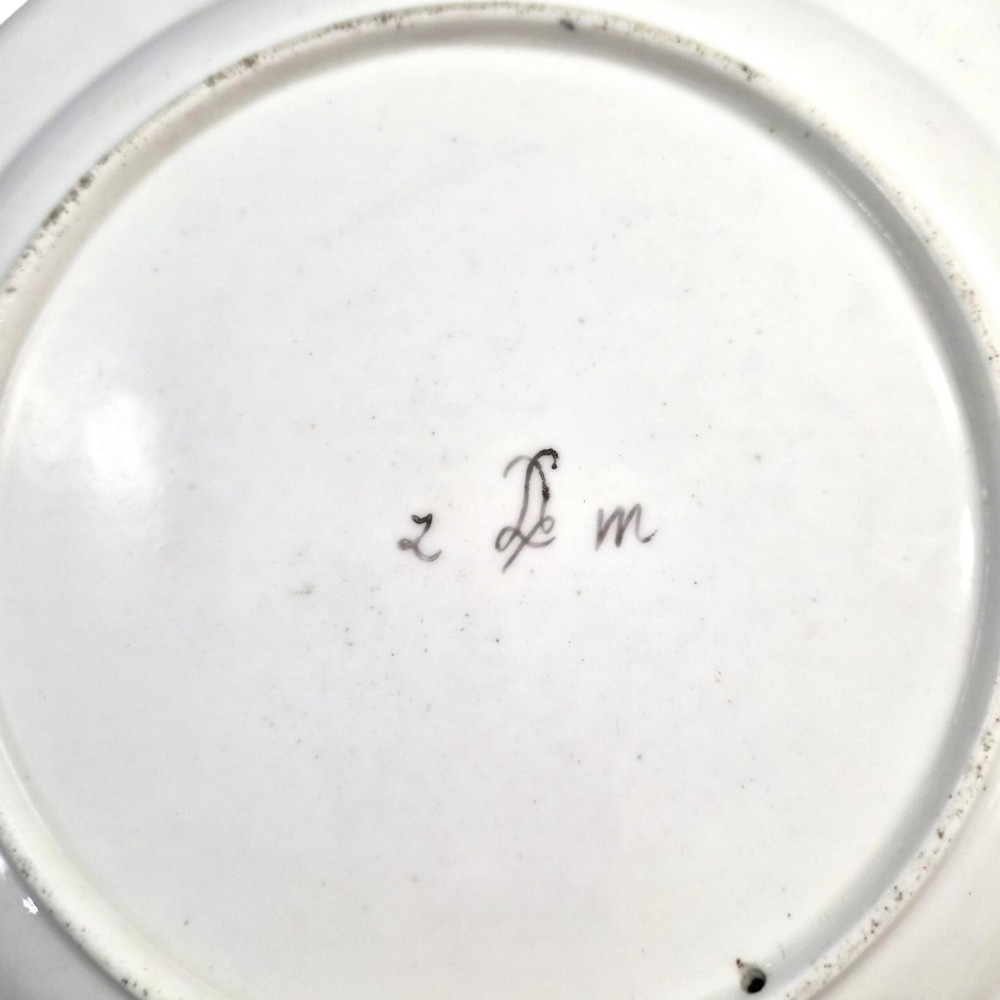 An 18th-century circular white soft-paste porcelain plate decorated with hand-painted floral sprays and a scalloped rim with blue feathered scroll details. View VI