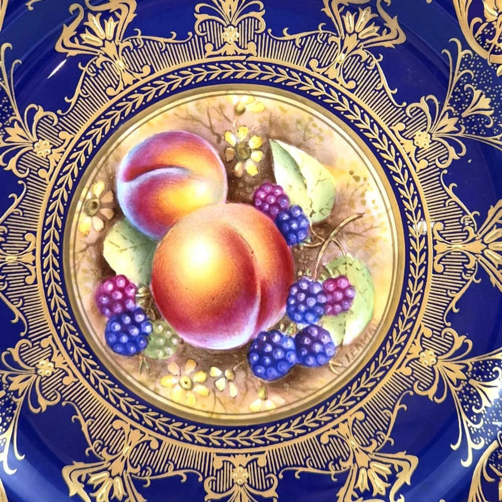 A circular porcelain cabinet plate featuring a central hand-painted still life of peaches and blackberries, surrounded by a broad cobalt blue border adorned with intricate gold gilding. View II